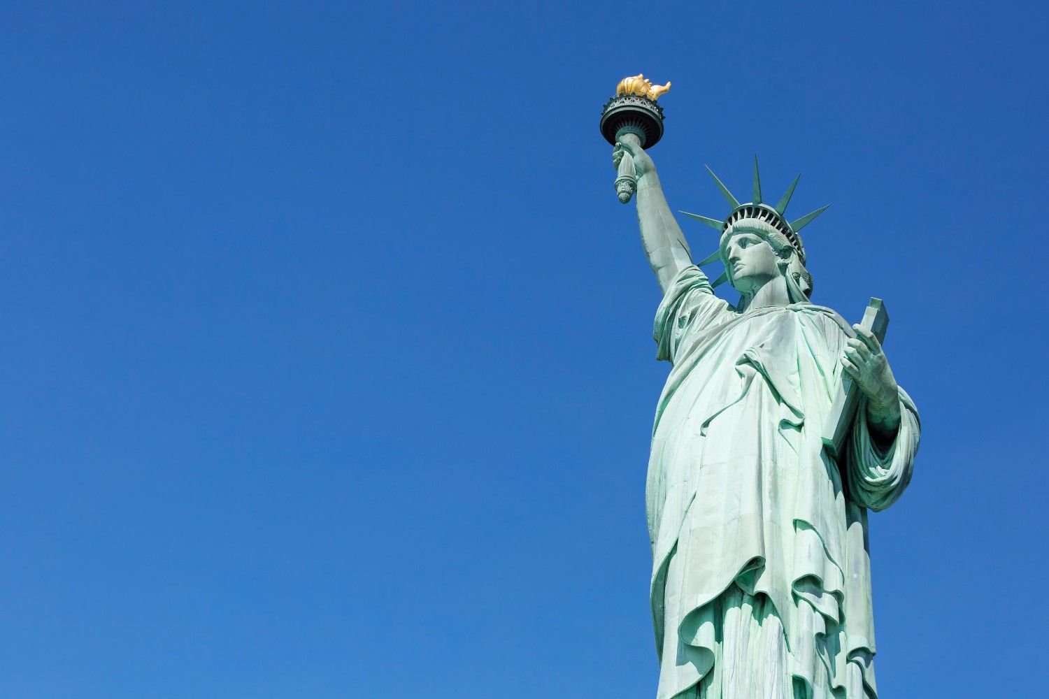 Statue of Liberty standing tall against a clear blue sky in New York City, New York for free