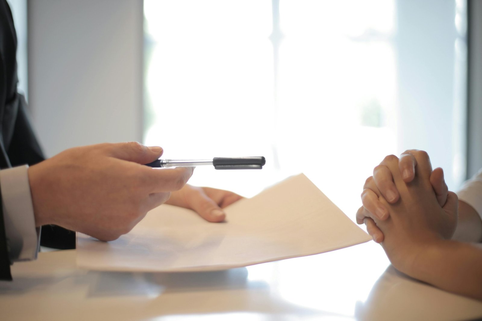 Mortgage advisor handing paperwork and pen to a borrower for a home loan application.