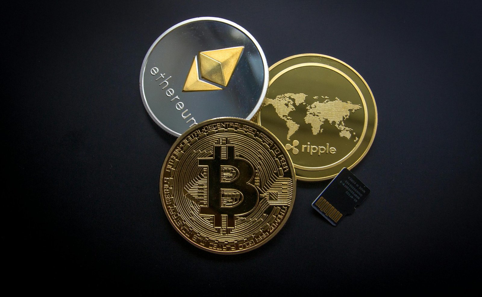 Bitcoin, Ethereum, and Ripple cryptocurrency coins displayed together on a dark background.